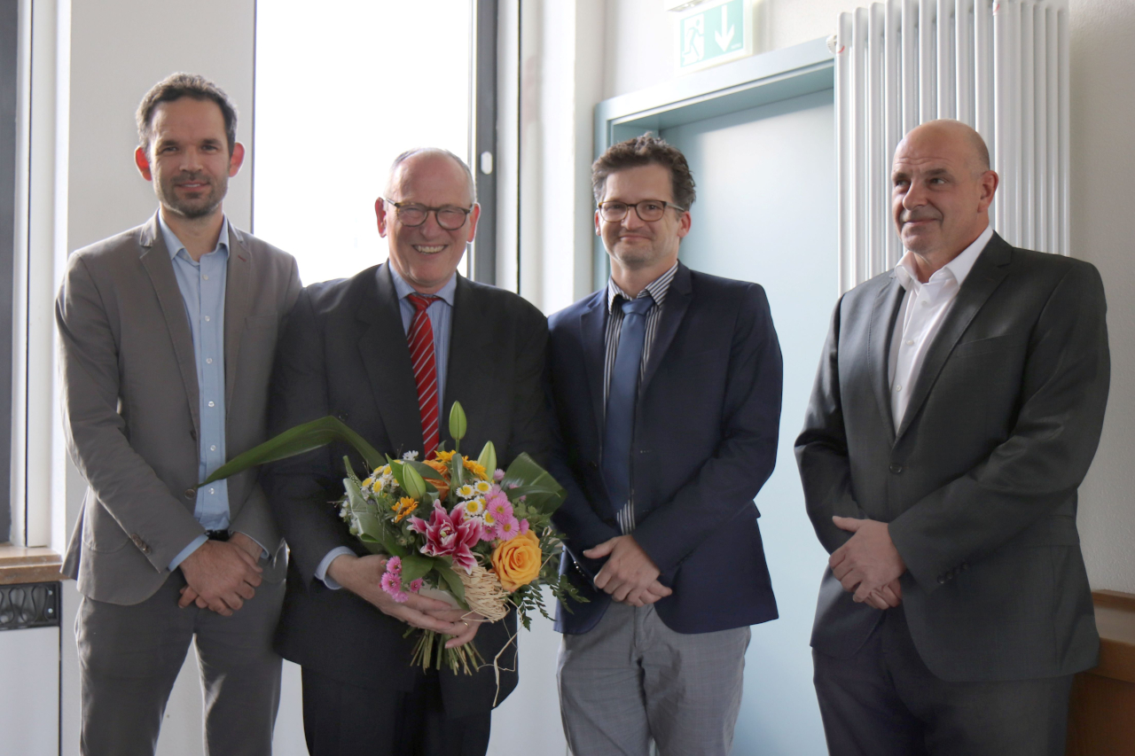 Zu sehen ist ein Gruppenbild mit Prof. Holger Jakstat und einem Blumenstrauß. Neben ihm stehen drei weitere Vertreter des UKLs, unter anderem Prof. Ingo Bechmann. 